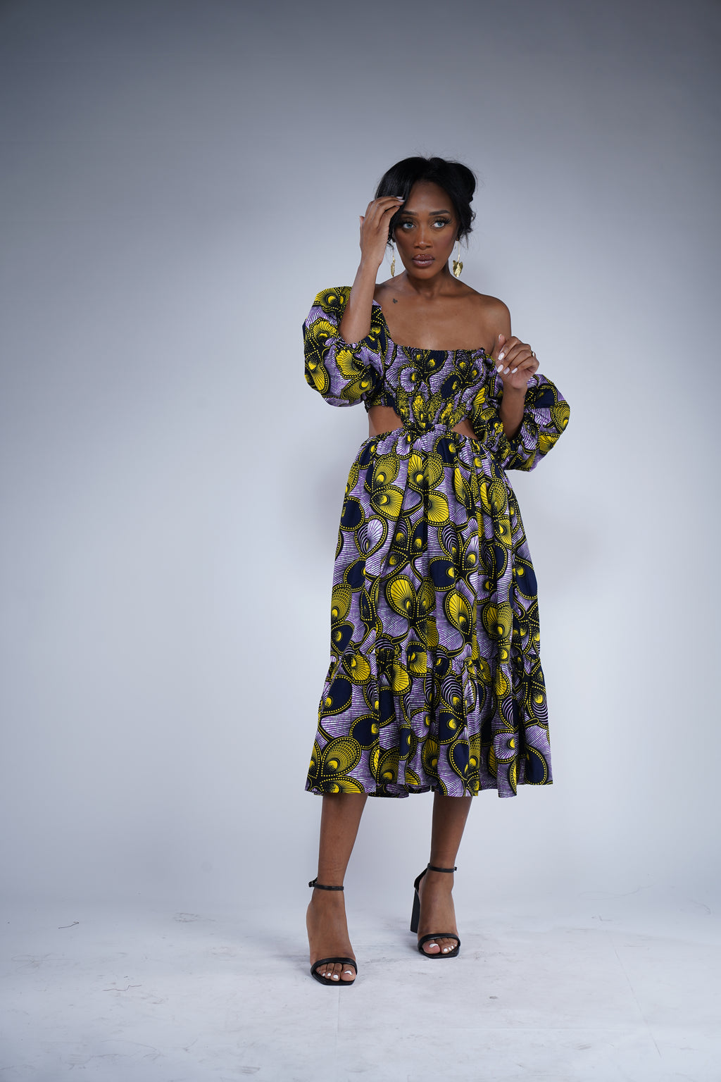 Brown girl wearing a purple and yellow cut out midi dress