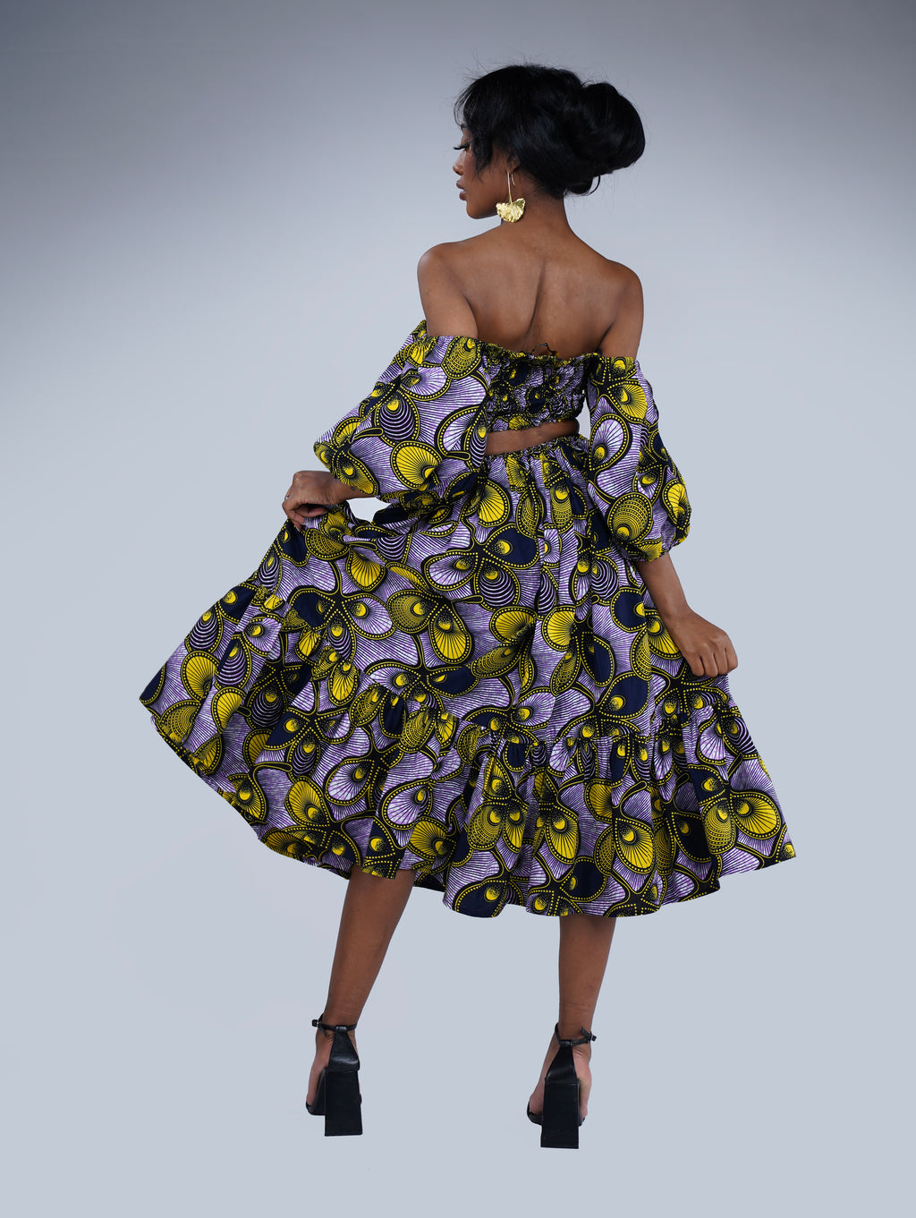 Brown girl wearing a purple and yellow cut out midi dress